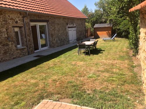 a yard with a table and chairs next to a building at La Maison du Moulin à Vent in La ForestiÃ¨re