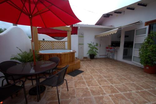 eine Terrasse mit einem Tisch und einem roten Regenschirm in der Unterkunft Zurisadai in Puerto Ayora