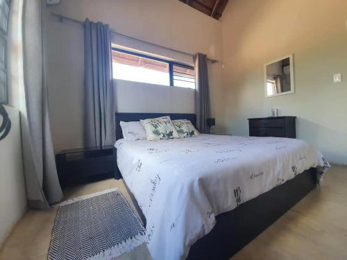 a bedroom with a large bed with a window at Kanimambo Chalet in Marloth Park