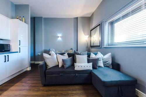 sala de estar con sofá azul y almohadas en Versace Inspired Apartment en Liverpool