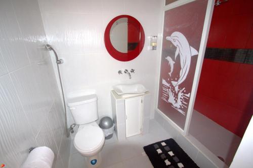a bathroom with a white toilet and a red mirror at Zurisadai in Puerto Ayora