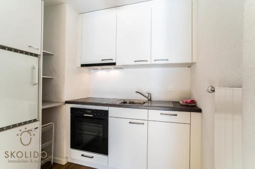 a kitchen with white cabinets and a sink at Haus Camillo in Saas-Fee