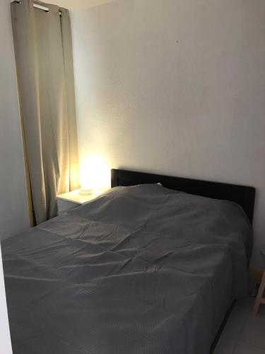 1 cama en un dormitorio con luz sobre una mesa en La Vigie du Corsaire, en Carqueiranne