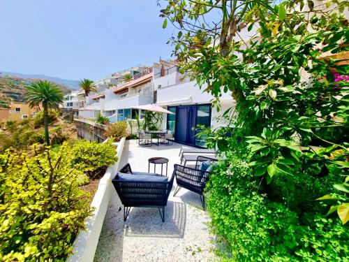 ロス・レアレホスにあるEl Drago Apartment, Amazing Ocean & Cliff Viewの植物のあるパティオに座る椅子