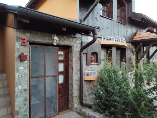 a building with a wooden door and some plants at Seosko turističko domacinstvo Imunsan in Niš