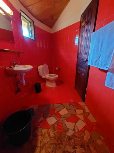 Baño rojo con aseo y lavamanos en Rundbungalow auf Lionsrest en Grand-Bassam