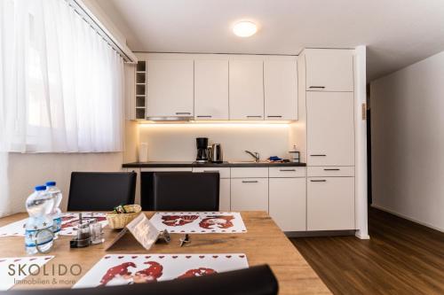 a kitchen with white cabinets and a wooden table at Haus Camillo in Saas-Fee
