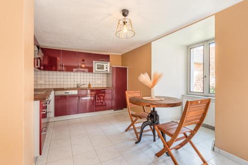 - une cuisine avec des placards rouges, une table et des chaises en bois dans l'établissement Havre de paix au pied du château et des remparts, à La Petite-Pierre