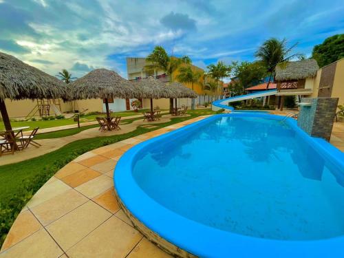 una piscina en un complejo con mesas y sombrillas en POUSADA OBAH VILLAGE, en Prea
