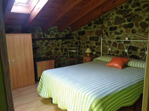 um quarto com uma cama e uma parede de pedra em Casa Rural La Barcenilla em Herada