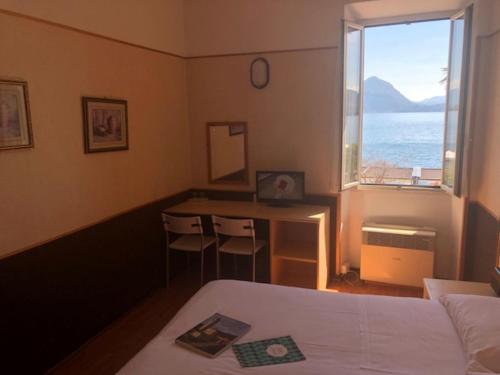 a bedroom with a bed and a desk and a window at Hotel Eden in Baveno