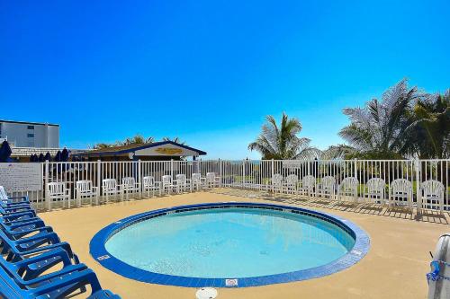 a swimming pool with lounge chairs and a fence at Carousel 1904 in Ocean City