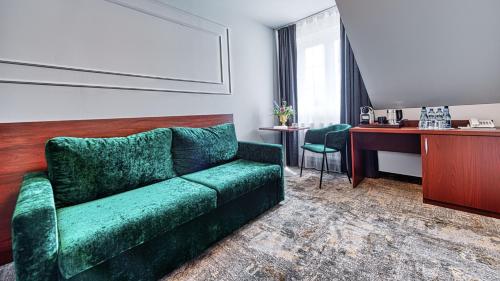 a living room with a green couch and a desk at St Lukas Medical & SPA in Świeradów-Zdrój