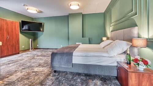 a bedroom with a large bed and a flat screen tv at St Lukas Medical & SPA in Świeradów-Zdrój