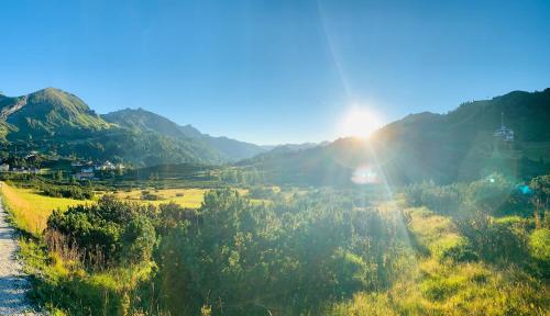 a view of a mountain valley with the sun shining at Hotel Binggl in Obertauern
