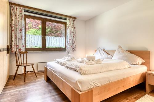 ein Schlafzimmer mit einem Bett, einem Stuhl und einem Fenster in der Unterkunft Landhaus Maeser in Schruns-Tschagguns