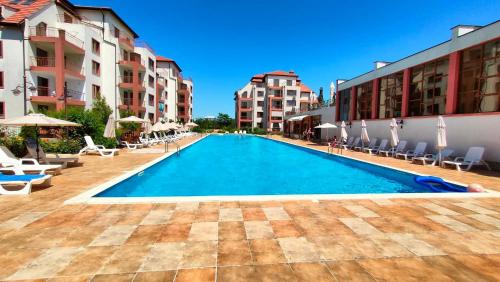 a swimming pool with chairs and umbrellas and buildings at Tindaya Apartments in Aheloy