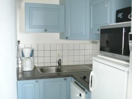 La cuisine est équipée de placards bleus, d'un évier et d'un four micro-ondes. dans l'établissement 3 pièces au pied des pistes avec balcon et casier à skis - FR-1-557-84, à Les Adrets