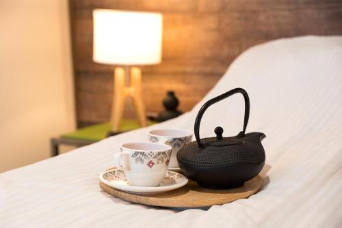 uma bandeja com duas chávenas e um bule de chá numa cama em Ultra Central Bohemian Apartment 1 em Cluj-Napoca