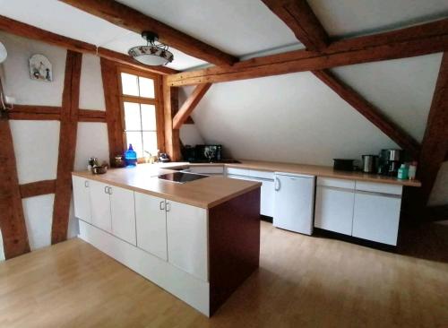Il comprend une cuisine avec des placards blancs et un plafond en bois. dans l'établissement Loft auf altem Gutshof, à Kirchensittenbach