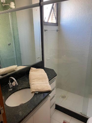 um banheiro com pia e box de vidro em Praia Dourada SUITE PREMIUM 603 Itaparica em Vila Velha