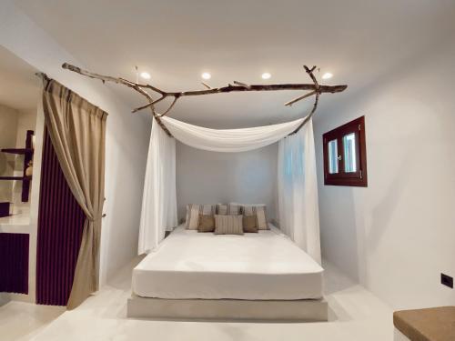 1 dormitorio con 1 cama con una rama encima en Archo Suites Pythagoreio, en Pythagoreio