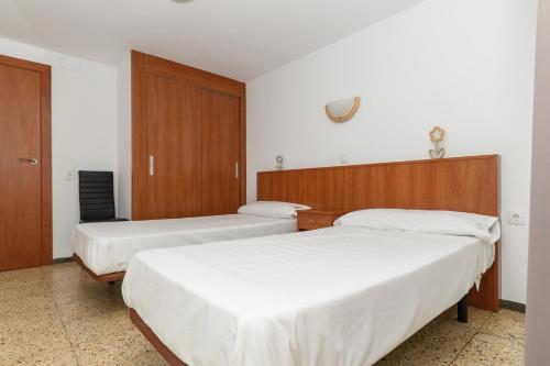 two beds in a hotel room with white sheets at Rentalmar Family Felix con parking incluido in Salou