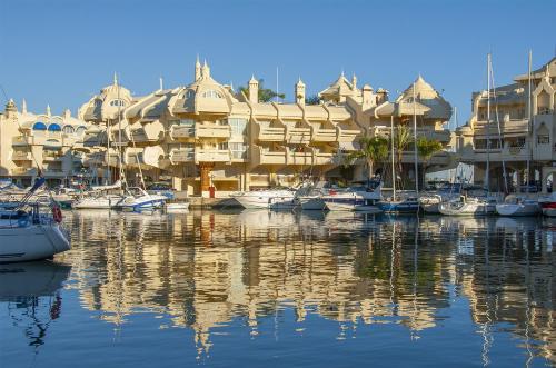 a marina with boats in front of a building at Tamarindos Apartments by ALFRESCO STAYS in Benalmadena Costa