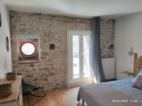 ein Schlafzimmer mit einer Steinmauer und einem Fenster in der Unterkunft La Vigneronne du 7 in Bouzigues