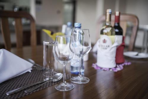 a table with two wine glasses and bottles of wine at Hotel Comster Mtwapa in Mtwapa