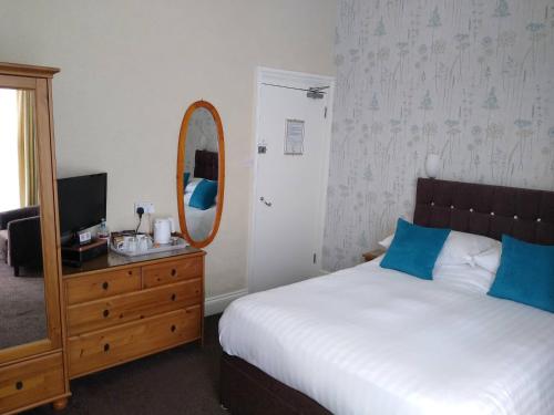 a bedroom with a bed and a mirror and a dresser at Hazeldene Guest House - with Free Offsite Health Club in Bowness-on-Windermere