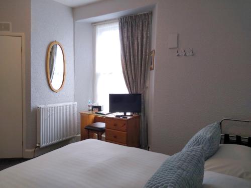 a bedroom with a bed and a desk and a window at Hazeldene Guest House - with Free Offsite Health Club in Bowness-on-Windermere