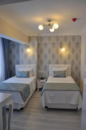 a bedroom with two beds and a ceiling at Hotel Iscen in Mustafakemalpaşa
