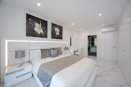 a white bedroom with a large bed and a bathroom at Luxury apartments with stunning sea views in Portimão
