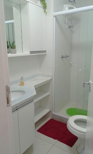 a white bathroom with a shower and a toilet at Apartamento com varanda - Sahy in Mangaratiba