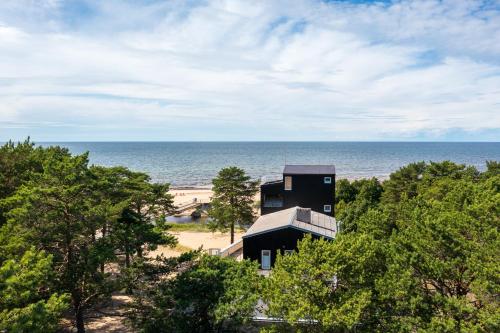 a building on the beach with the ocean in the background at Jõesuu Guesthouse in Vääna-Jõesuu