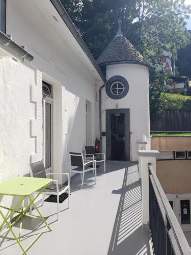 een balkon met een tafel en stoelen en een klok op een gebouw bij Hébergement Artense in Le Mont-Dore