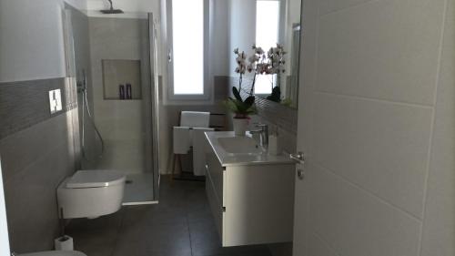 a white bathroom with a sink and a toilet at Villetta vicino al mare in Porto Palo