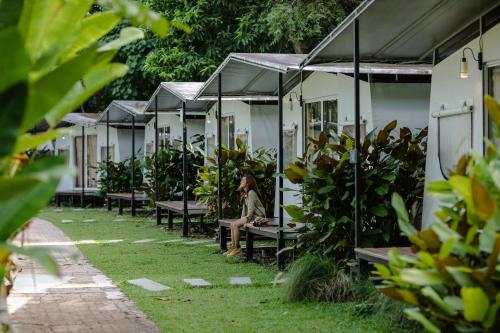 a woman sitting on a bench in a row of houses at Kachonghills Tented Resort Trang in Trang