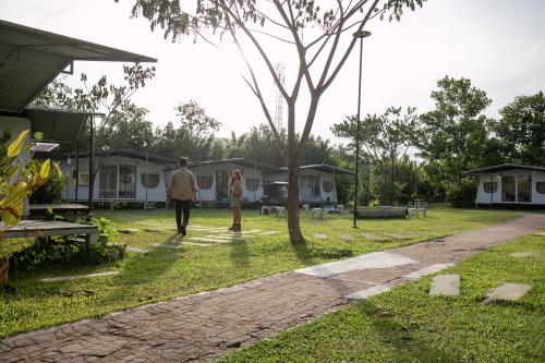 a man walking through a yard with houses at Kachonghills Tented Resort Trang in Trang
