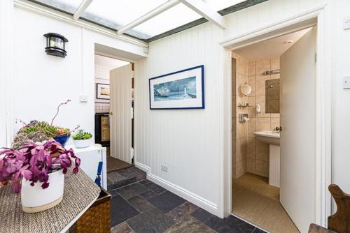 a bathroom with a hallway with a sink and a toilet at 4 Bed - Beach Cottage in Torquay