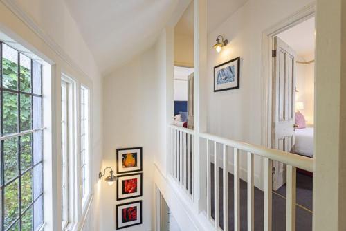 a white hallway with a staircase with paintings on the walls at 4 Bed - Beach Cottage in Torquay