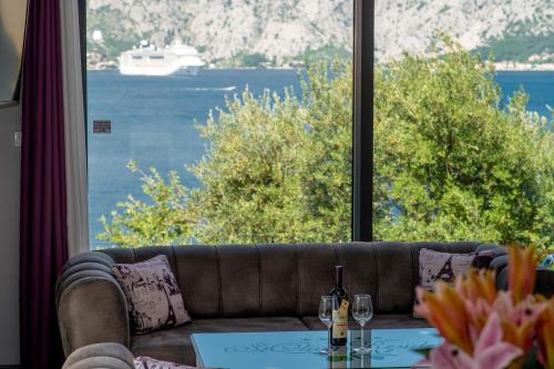 a couch in front of a large window with a boat in the water at StOliva RESIDENCE with infinity pool in Kotor