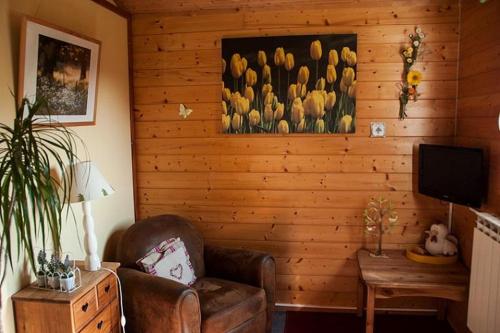 uma sala de estar com uma cadeira e um quadro de tulipas em Domaine des Epinettes em Saint-Romain-de-Jalionas