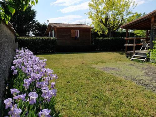 a bunch of purple flowers in a yard with a house at Domaine des Epinettes in Saint-Romain-de-Jalionas