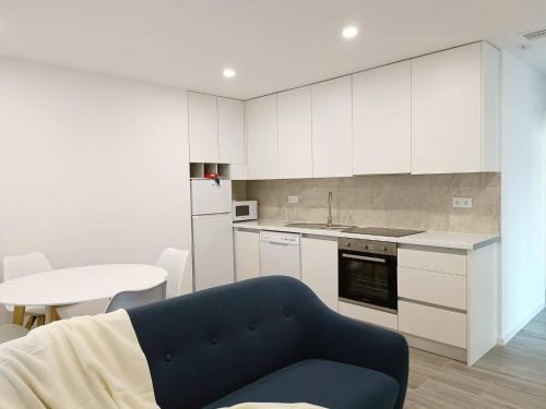 uma cozinha com armários brancos e um sofá azul em AndreiHouse em Amares