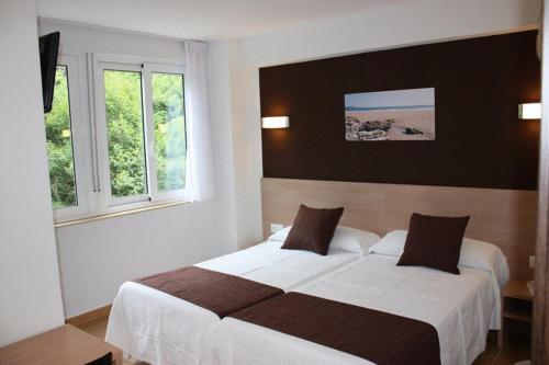 Habitación de hotel con 2 camas y 2 ventanas en Hostal Rocamar, en Santander