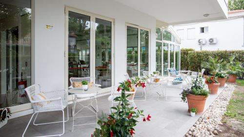 a patio with chairs and tables and potted plants at BeYou Hotel Villa Rosa in Riccione