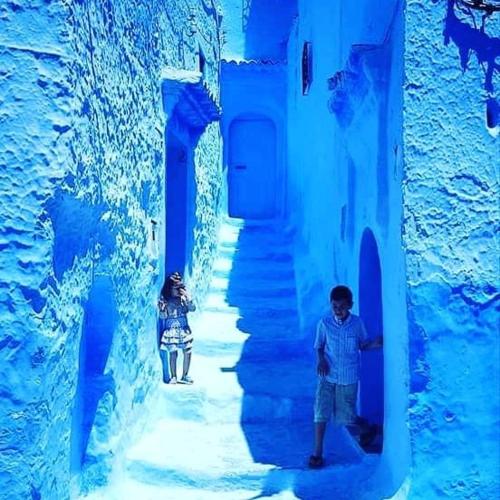 two people standing in an alley in a blue building at CASA dreams Chaouen in Chefchaouene