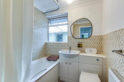 a bathroom with a tub and a sink and a mirror at LOCHIEL in Tatsfield